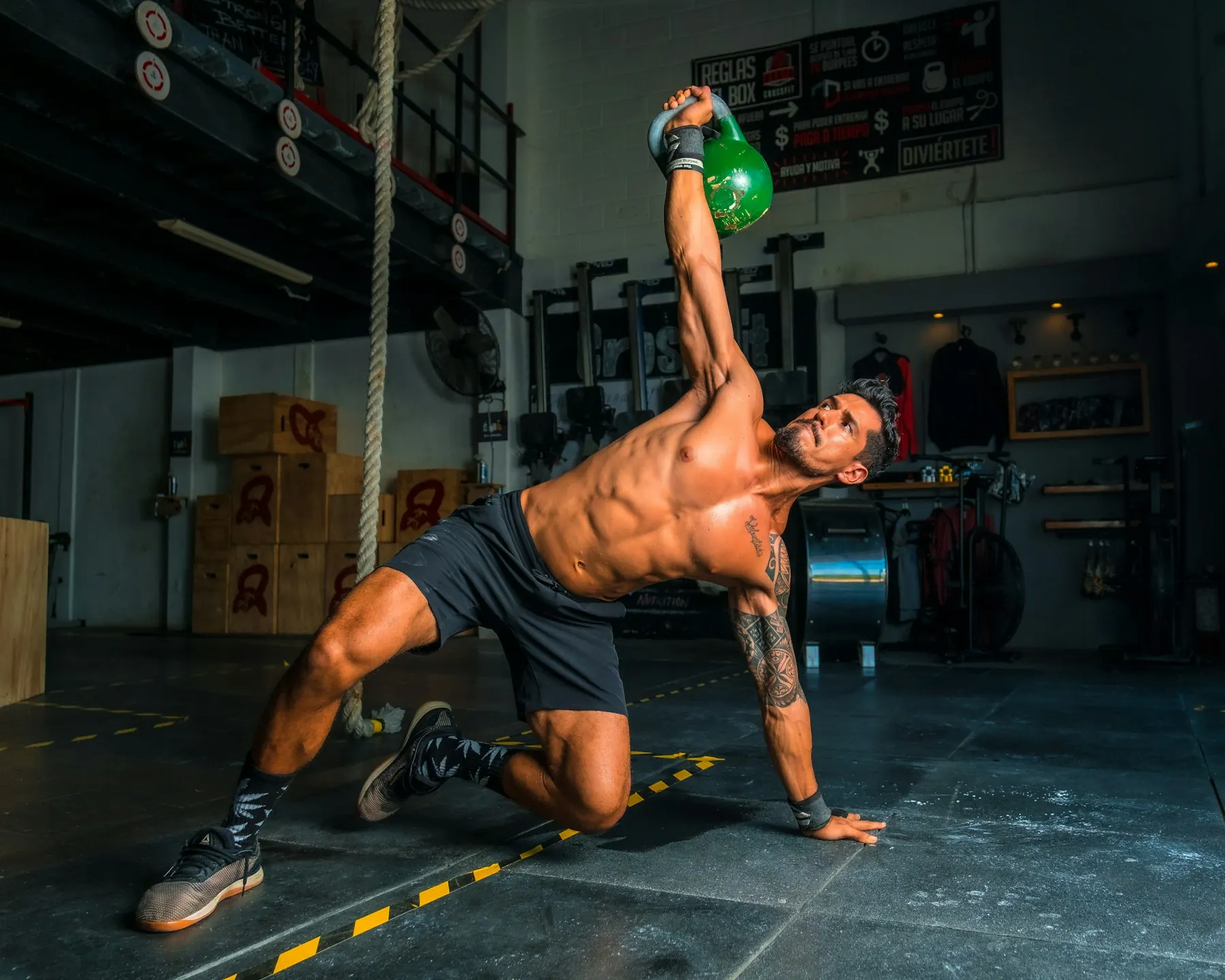 Athlete pressing a kettlebell overhead in a dark gym